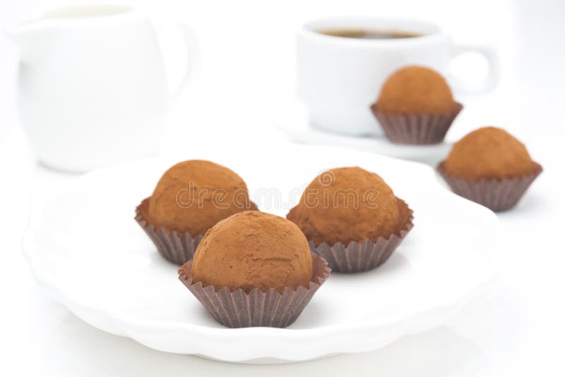 Chokladtryfflar på en platta och en kopp kaffe royaltyfri bild Chokladtryfflar på en platta och en kopp kaffe royaltyfri bild