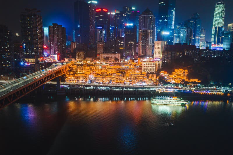 Aerial view of Hong Ya dong Cave, Historic Chinese folk religion town with lights on by Jialing River with skyscrapers. Aerial view of Hong Ya dong Cave, Historic Chinese folk religion town with lights on by Jialing River with skyscrapers