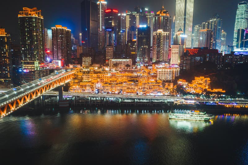 Aerial view of Hong Ya dong Cave, Historic Chinese folk religion town with lights on by Jialing River with skyscrapers. Aerial view of Hong Ya dong Cave, Historic Chinese folk religion town with lights on by Jialing River with skyscrapers