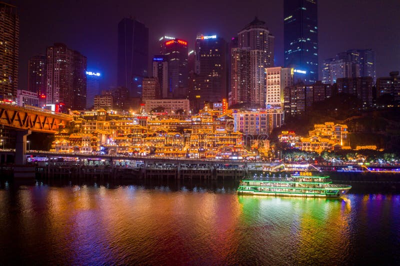 Aerial view of Hong Ya dong Cave, Historic Chinese folk religion town with lights on by Jialing River with skyscrapers. Aerial view of Hong Ya dong Cave, Historic Chinese folk religion town with lights on by Jialing River with skyscrapers