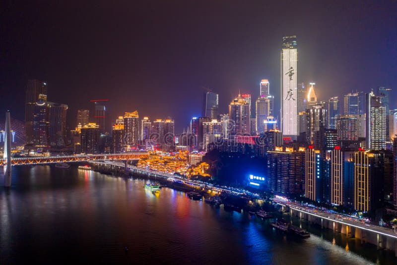 Aerial view of Hong Ya dong Cave, Historic Chinese folk religion town with lights on by Jialing River with skyscrapers. Aerial view of Hong Ya dong Cave, Historic Chinese folk religion town with lights on by Jialing River with skyscrapers