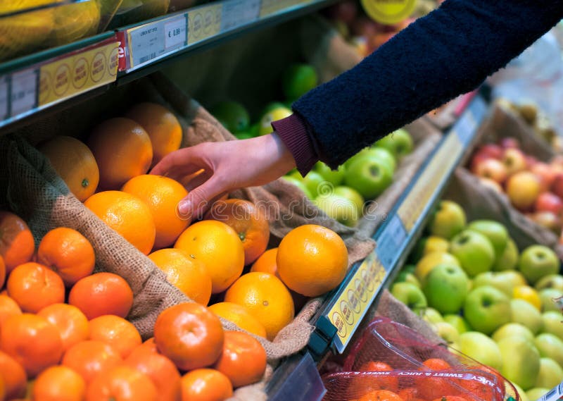 Choosing an orange in grocery store royalty free stock image