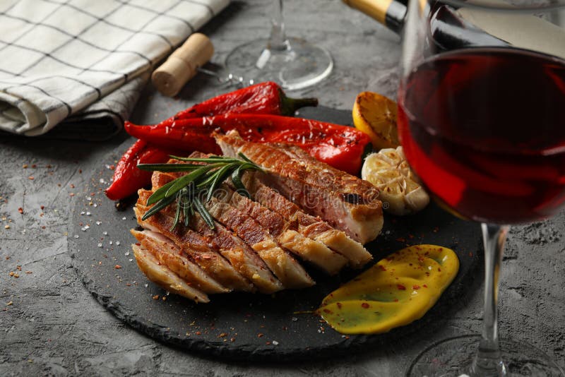 Chopped fried pork steak, vegetables and wine on background. Grilled food