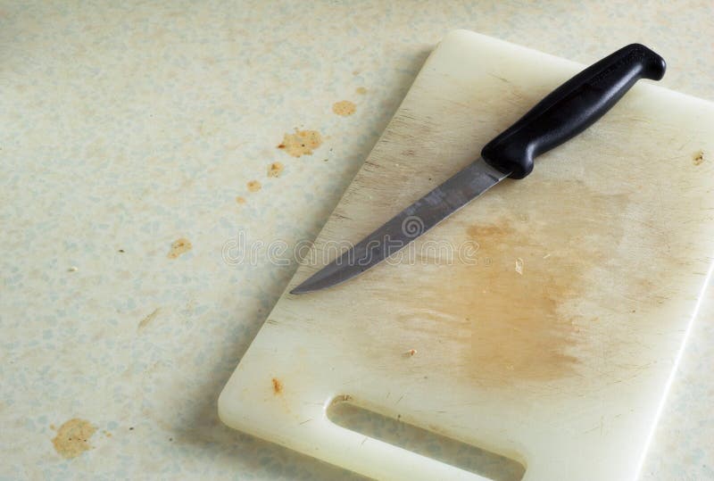 Dirty unhygenic kitchen chopping board and knife.