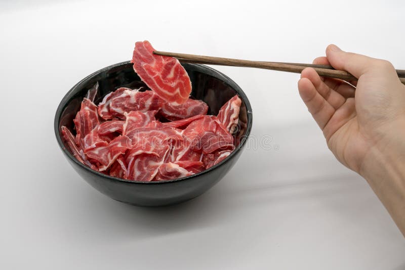 Chopstick trzyma świeżej pokrojonej wołowiny tylni giczoł od czarnego cera zdjęcia royalty free Chopstick trzyma świeżej pokrojonej wołowiny tylni giczoł od czarnego cera zdjęcia royalty free