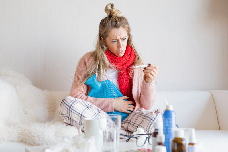 Sick woman measuring temperature with thermometer while sitting in bed. Sick woman measuring temperature with thermometer while sitting in bed