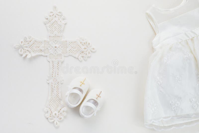 Christening background with baptism dress, shoes, and cross on pastel background