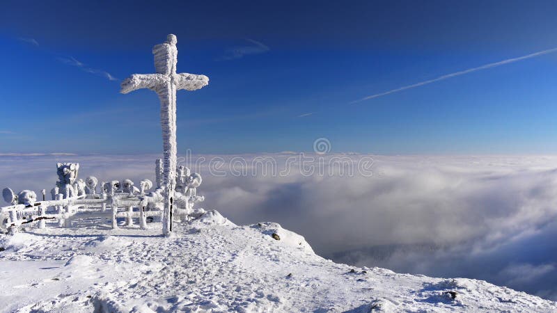 Cross on top in a snowy winter mountain landscape, blue sky. Winter landscape background. Cross on top in a snowy winter mountain landscape, blue sky. Winter landscape background.