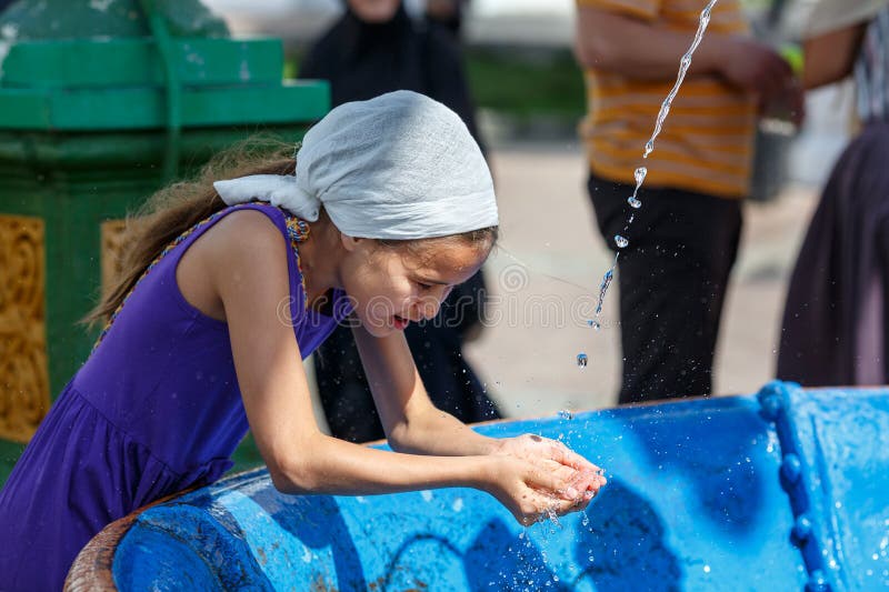 Christian Russian girl in traditional head scarf is drinking water from the Holy spring in the Sergiev Posad monastery. stock image Christian Russian girl in traditional head scarf is drinking water from the Holy spring in the Sergiev Posad monastery. stock image