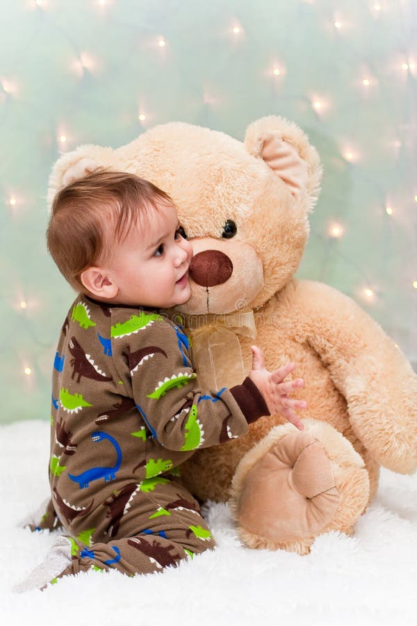 Christmas baby in pajamas holding teddy bear. 