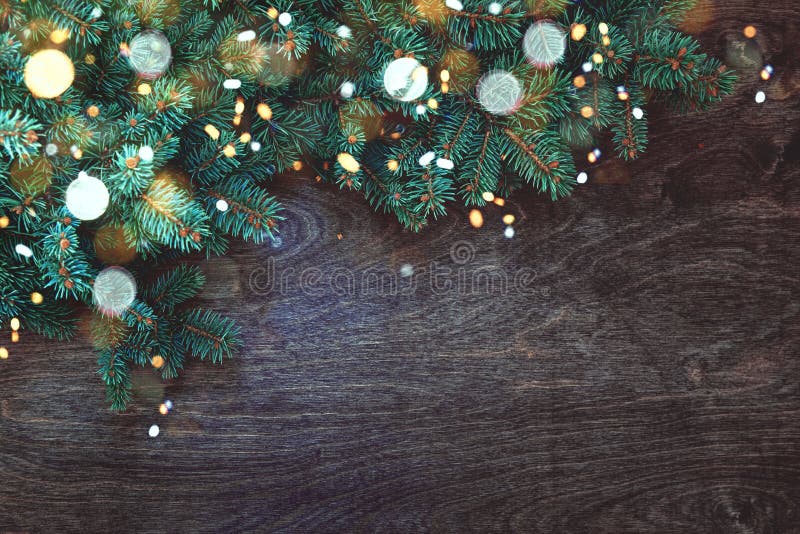 Christmas background with border of fluffy green fir branches on a textured dark brown wood