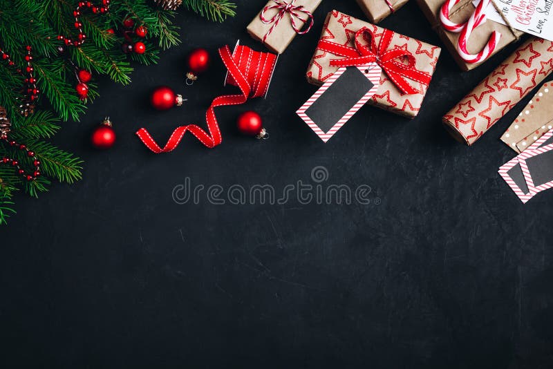 Christmas background with fir branches and cones gift boxes with red bow ribbon on a dark concrete background. Top view, copy space