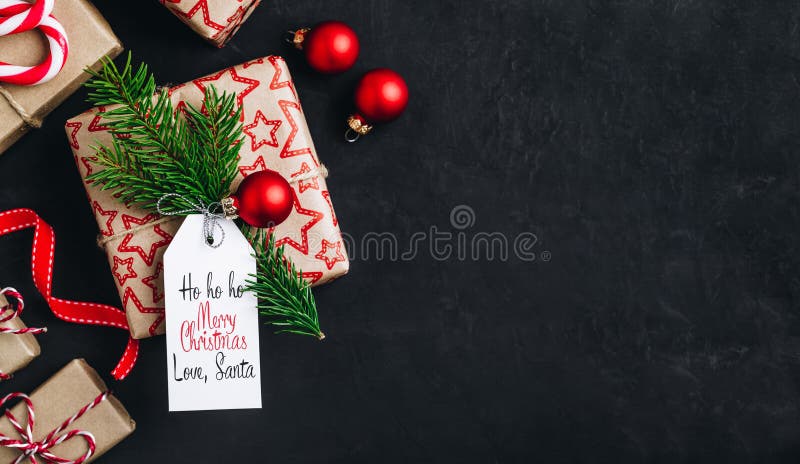 Christmas background with fir branches and a gift box with a red bow on a dark concrete background. Top view, copy space