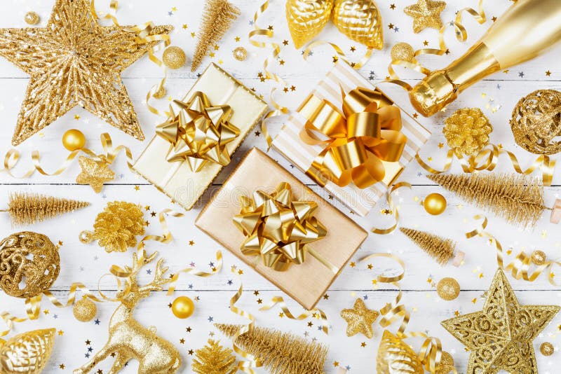 Christmas background with golden gift or present box, champagne and holiday decorations on white table top view. Greeting card.