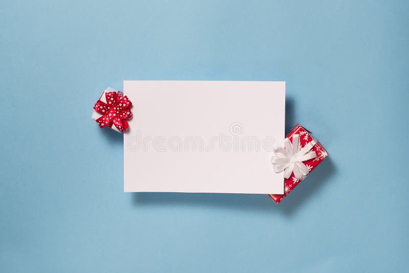 Christmas backround. Two red gift boxes with blank note on blue