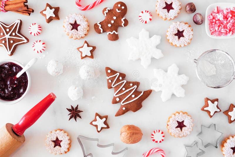 Christmas baking table scene with cookies and sweets. Top down view over white marble.