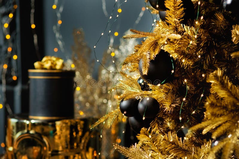 Selective focus. Christmas black ball on a Golden Christmas tree. Christmas toys, gifts in a black and gold box and garlands of