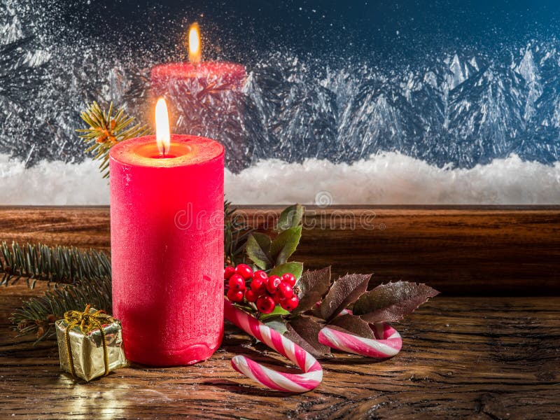 Christmas candle, fir branch, candy canes and frozen window on background.