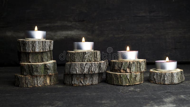 Christmas candles burning, decoration with wooden logs resting o