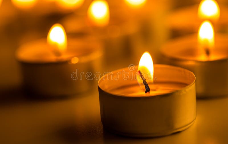 Christmas candles burning at night. Abstract candles background. Golden light of candle flame.