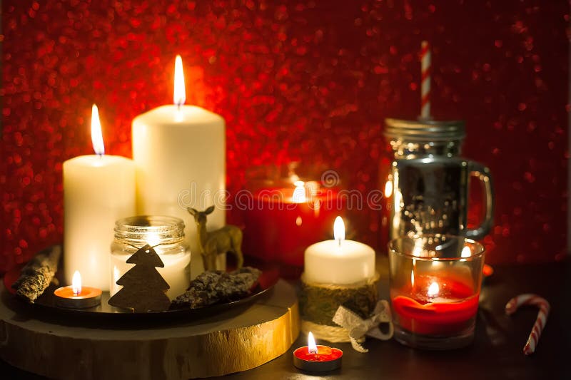 Christmas candles and holiday decorations on red blurred abstract background. Mason jar and sugar canes