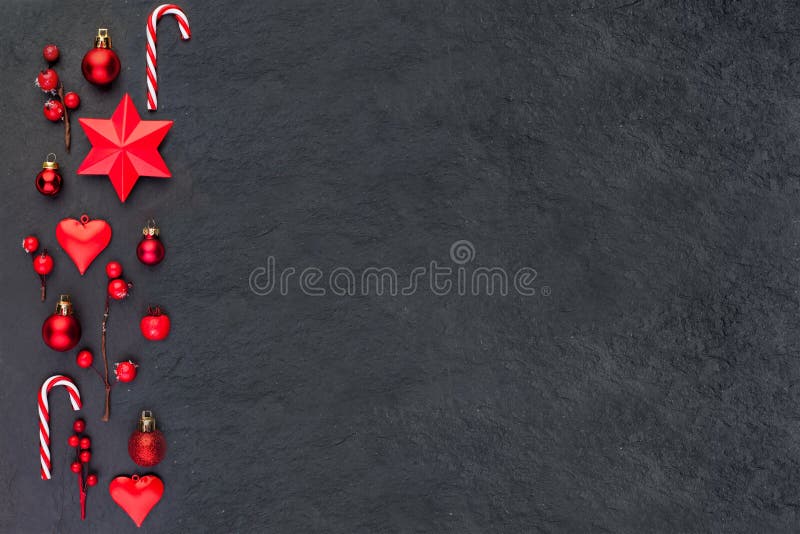 Christmas card on black. Red Christmas decor stars, candy and holly berries flat lay top view on dark background with copy space stock image Christmas card on black. Red Christmas decor stars, candy and holly berries flat lay top view on dark background with copy space stock image