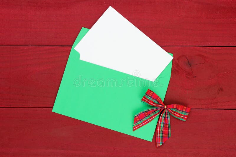 Christmas card envelope and letter with bow and red wood background