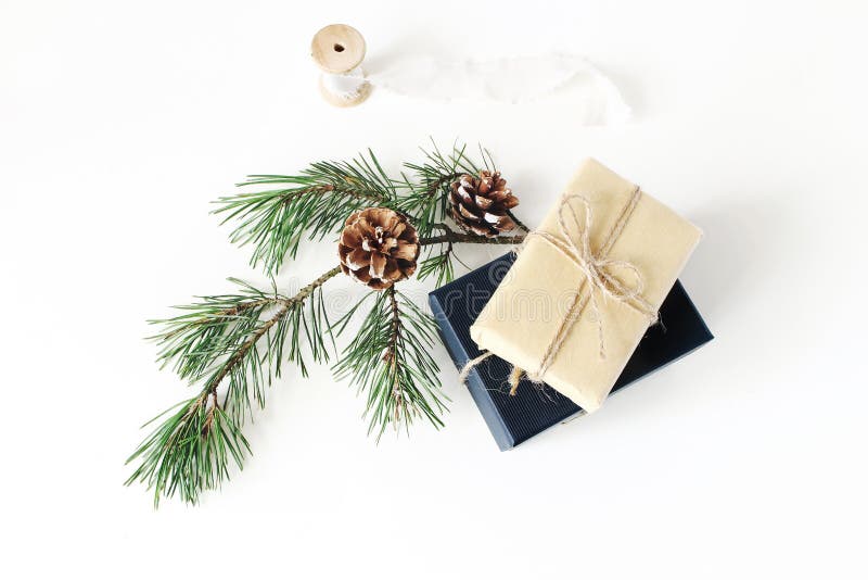Christmas composition. Festive wrapped Christmas gift boxes with pine branch with cones and silk ribbon on white table