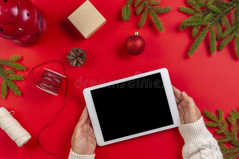 Christmas composition. Top view of tablet computer in woman hands. Christmas decoration and green fir branches on red stock photography Christmas composition. Top view of tablet computer in woman hands. Christmas decoration and green fir branches on red stock photography