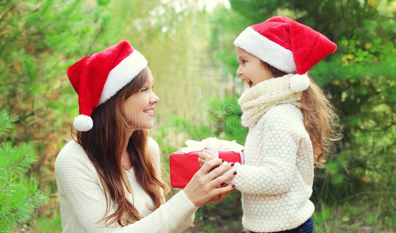 Christmas concept - child and mother in santa red hat with box gift stock image Christmas concept - child and mother in santa red hat with box gift stock image