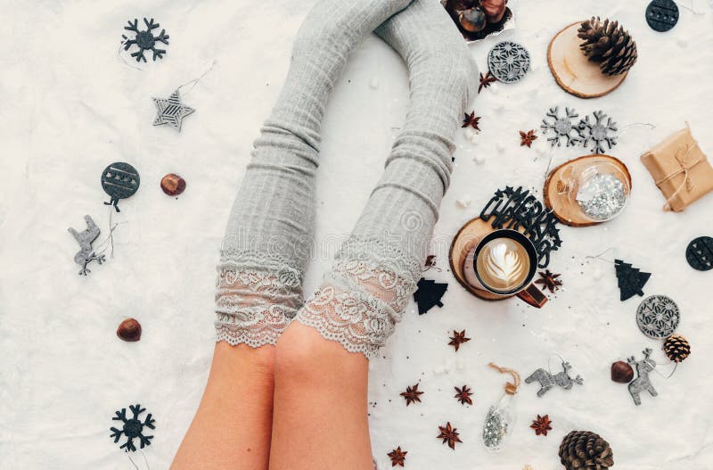 Christmas concept. Young woman legs with cup of coffee or cocoa.