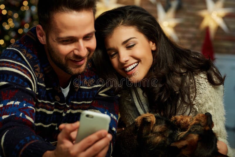 Christmas couple with phone at home in Winter stock photography