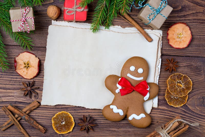 Christmas greeting card, old blank paper sheet, gingerbread man with frame made of fir, and spices, wooden background