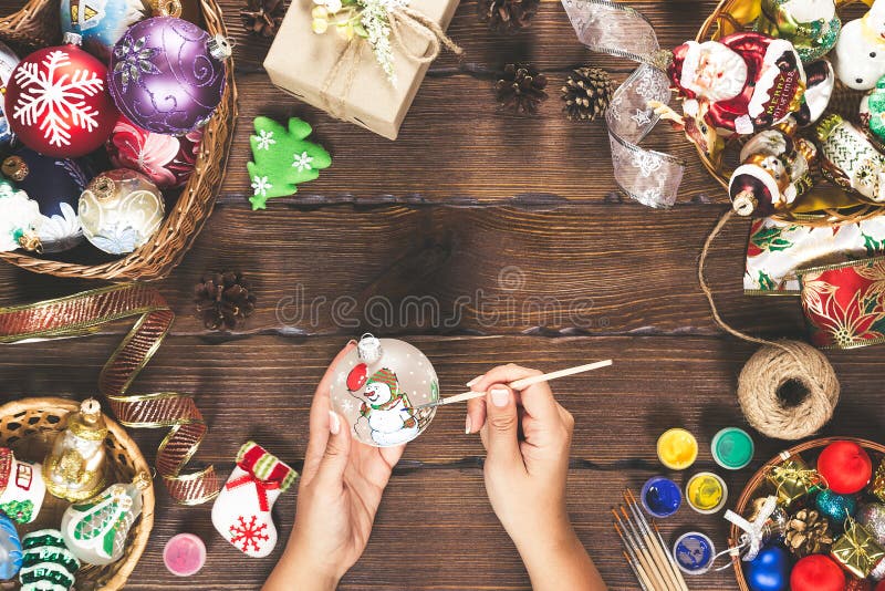 Christmas decorations, balls, toy and gift boxes on old wooden board. Female hands draw New Year decorations. Beautiful frame with stock photo Christmas decorations, balls, toy and gift boxes on old wooden board. Female hands draw New Year decorations. Beautiful frame with stock photo