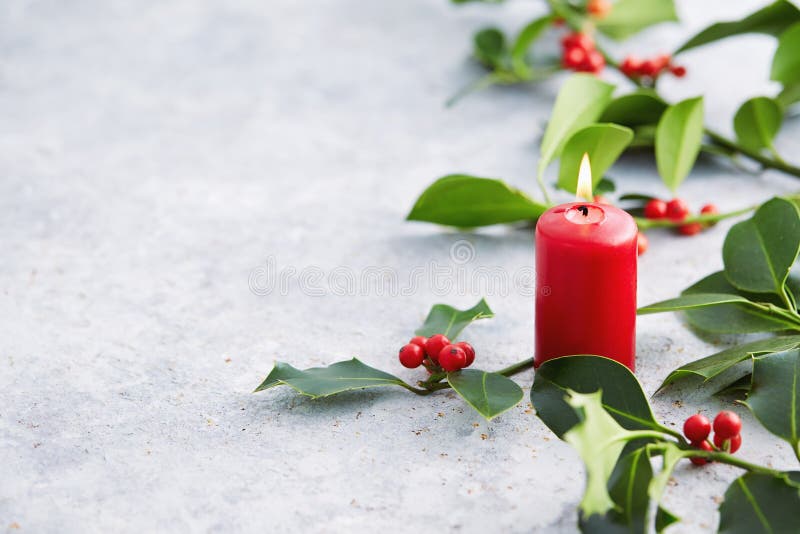 Christmas decorations, candle and holly leaves with red berries.