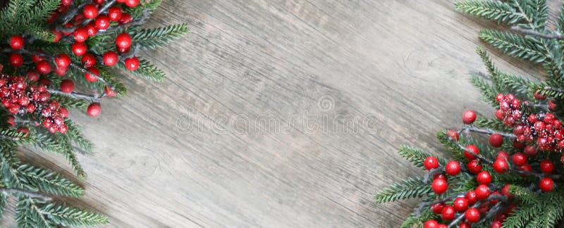 Christmas Evergreen Pine Branches and Red Berries in Corners Over Wood Background. Holiday Garland Border Backdrop with Copy Space