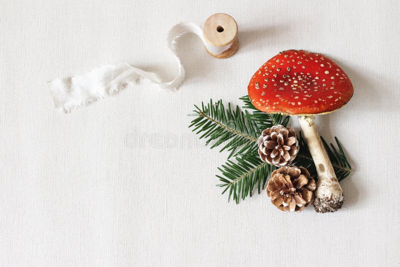 Christmas festive styled stock composition. Red fly agaric mushroom, silk ribbon, pine cones and fir tree branches on