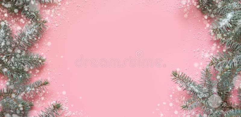 Christmas frame of fir branches, snowy white decorations on pink table. Xmas background. Flat lay. Top view with copy space