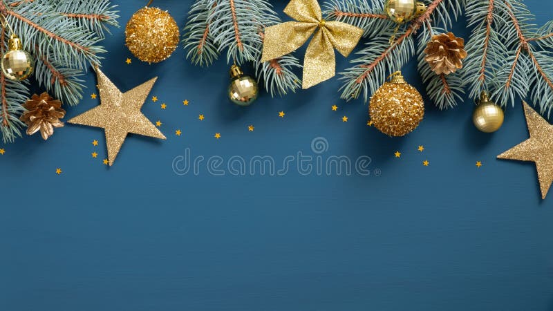 Christmas frame top border made of fir tree branches, golden decorative stars, balls over blue background. Flat lay, top view. royalty free stock photos