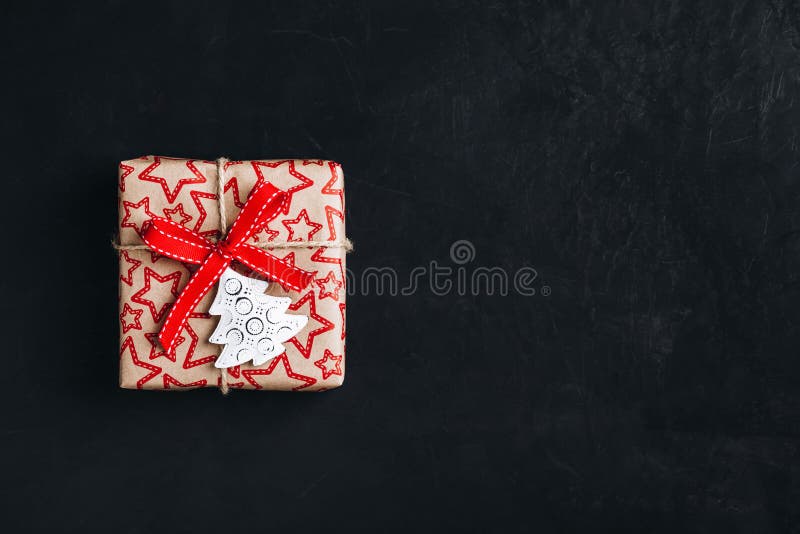 Christmas gift box with red bow ribbon on a dark concrete background. Top view, copy space