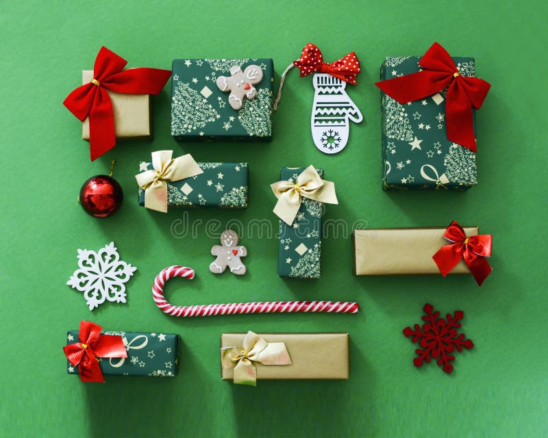 Christmas gift composition. Flat lay green and red winter decorations presents on green background with gold detail.