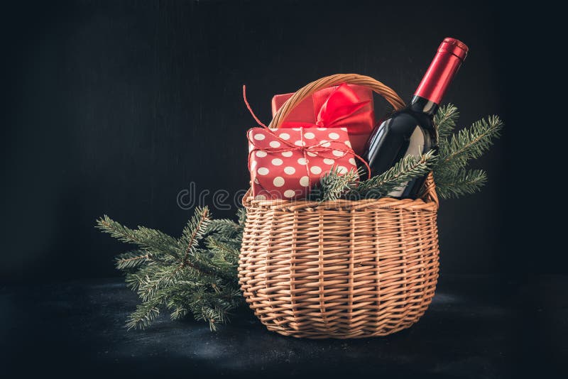 Christmas gift hamper with red wine and gift on black. Space for your greetings. Xmas card