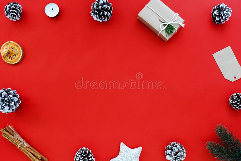 Christmas gift, pine cone and Xmas decoration on red background.