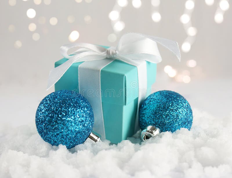 Christmas gift and baubles nestled in snow. Christmas gift with white bow and baubles nestled in snow with defocussed bokeh lights stock photos Christmas gift and baubles nestled in snow. Christmas gift with white bow and baubles nestled in snow with defocussed bokeh lights stock photos