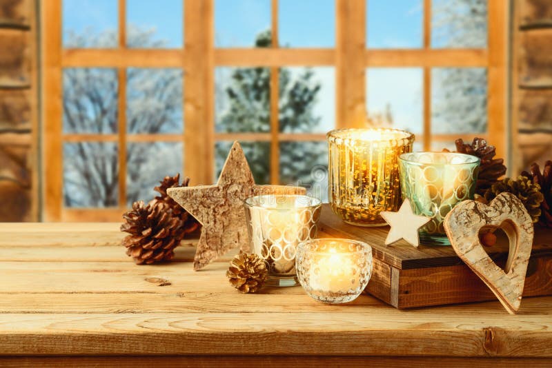 Christmas holiday background with candle decor and pine cone on wooden table over window. Winter greeting card. Christmas holiday background with candle decor