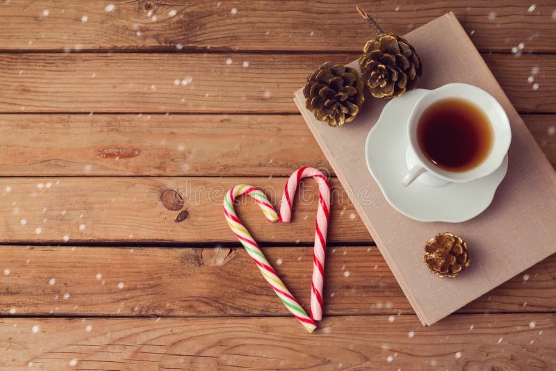 Christmas holiday tea cup on old books with love shaped candy on wooden table with copy space