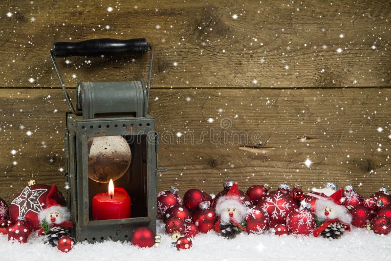 Christmas latern with red candle and balls on wooden background.