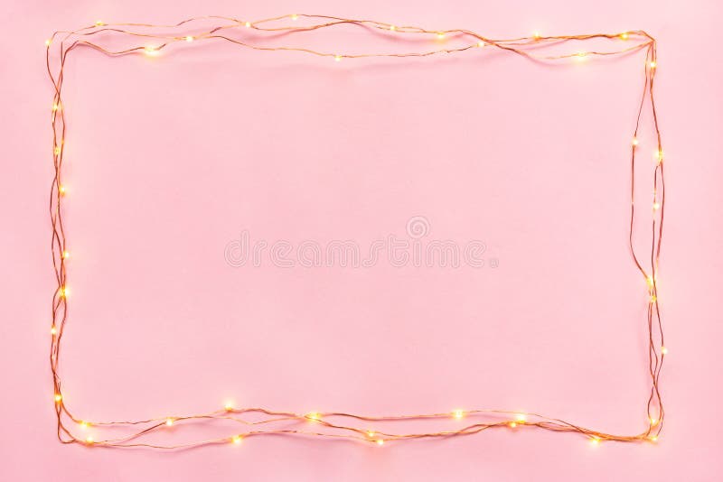 Christmas lights garland border over pink background. Flat lay, copy space. royalty free stock photos