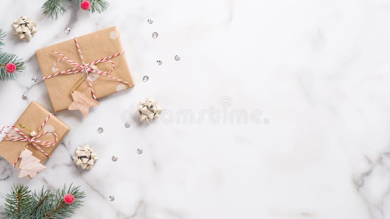 Christmas or New Year banner. Xmas greeting card. Christmas gifts and fir tree branches on white marble background. Flat lay, top stock image Christmas or New Year banner. Xmas greeting card. Christmas gifts and fir tree branches on white marble background. Flat lay, top stock image
