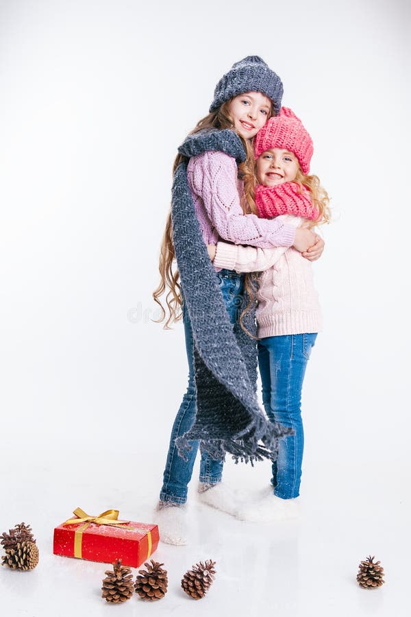 Christmas. New Year. Two little sisters holding present in winter clothes. Pink and grey hats and scarfs. Family. Winter stock image Christmas. New Year. Two little sisters holding present in winter clothes. Pink and grey hats and scarfs. Family. Winter stock image